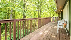 Eine Holzterrasse mit Geländer, mit Blick auf einen bewaldeten Bereich.