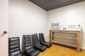 A waiting area with four black chairs, a microwave, and a shelf with snacks. - Smoky Mtn Home with Theater, Game Room & Hot Tub (Sevierville)