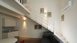 Un ambiente compatto con una scala, un'area pranzo e un divano.