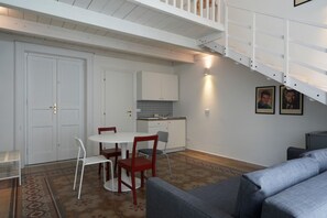 Ein Essbereich mit weißem Tisch und Stühlen, eine Küche mit weißen Schränken und eine Treppe mit weißen Geländern.