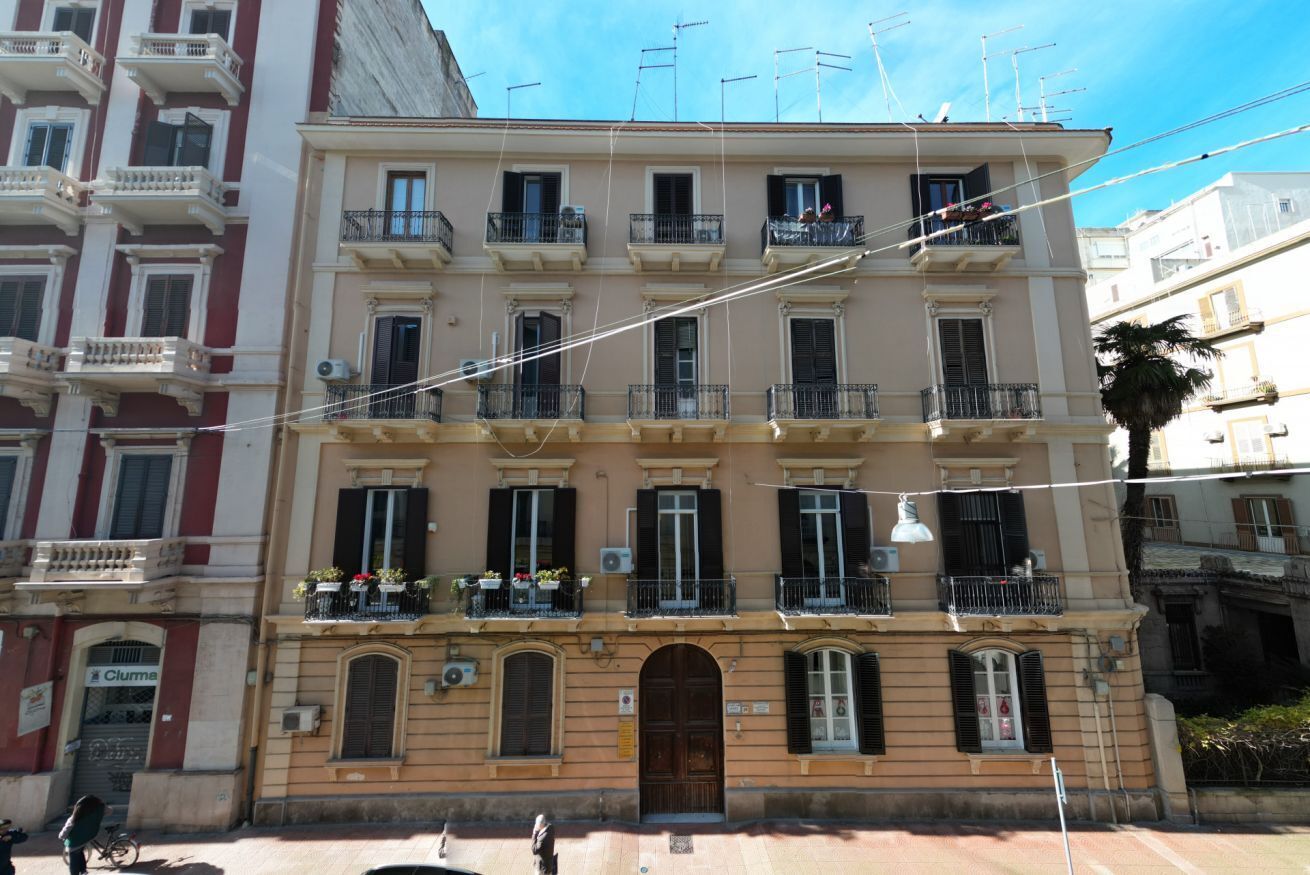 A multi-story building with balconies, a central entrance, and a sign for 'Cluma' on the ground floor.