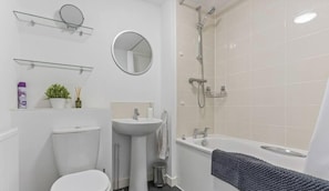 Un baño con inodoro, lavabo, espejo, ducha y bañera.