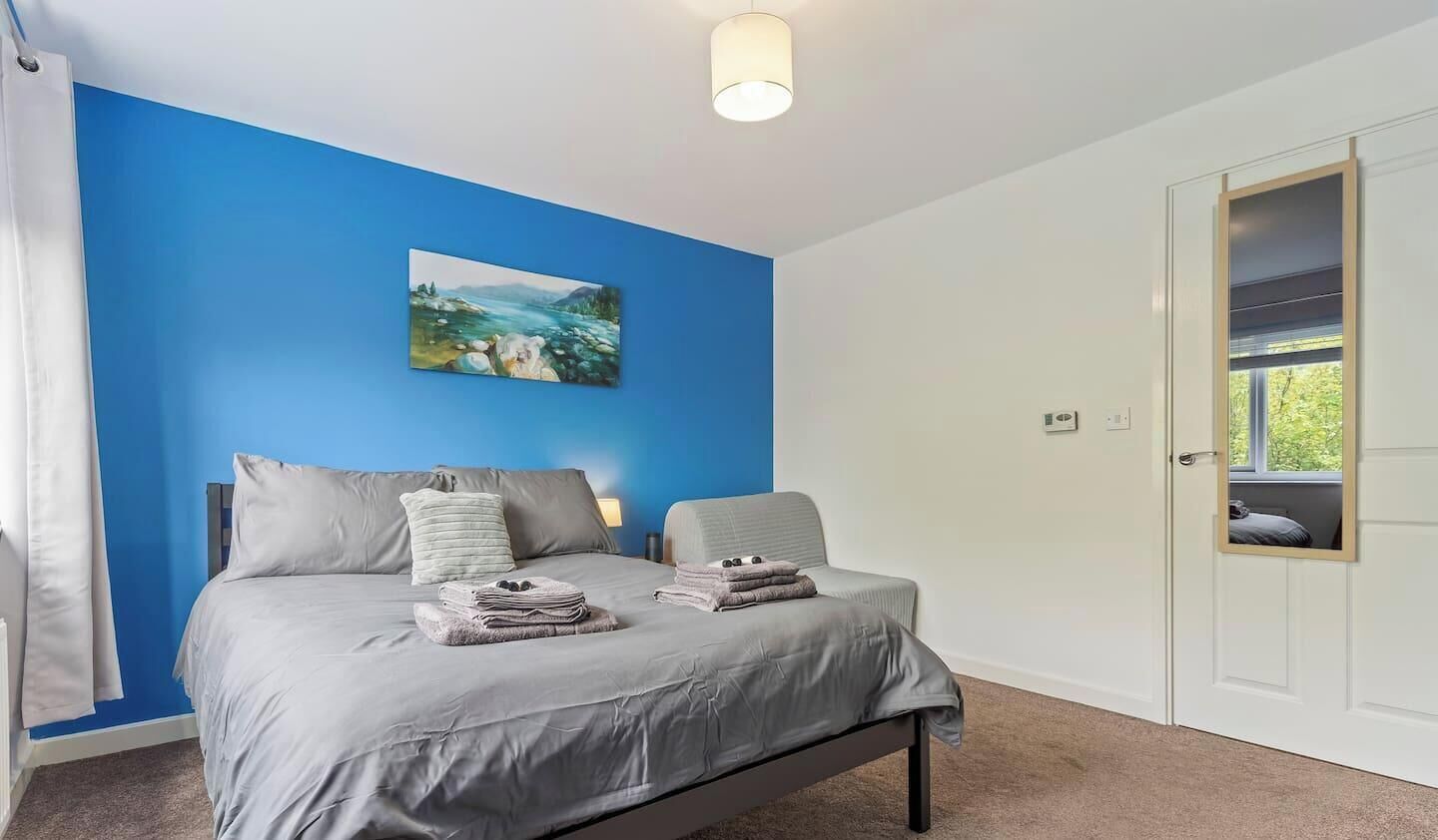 A bedroom with a bed, a painting on the wall, and a door with a view.