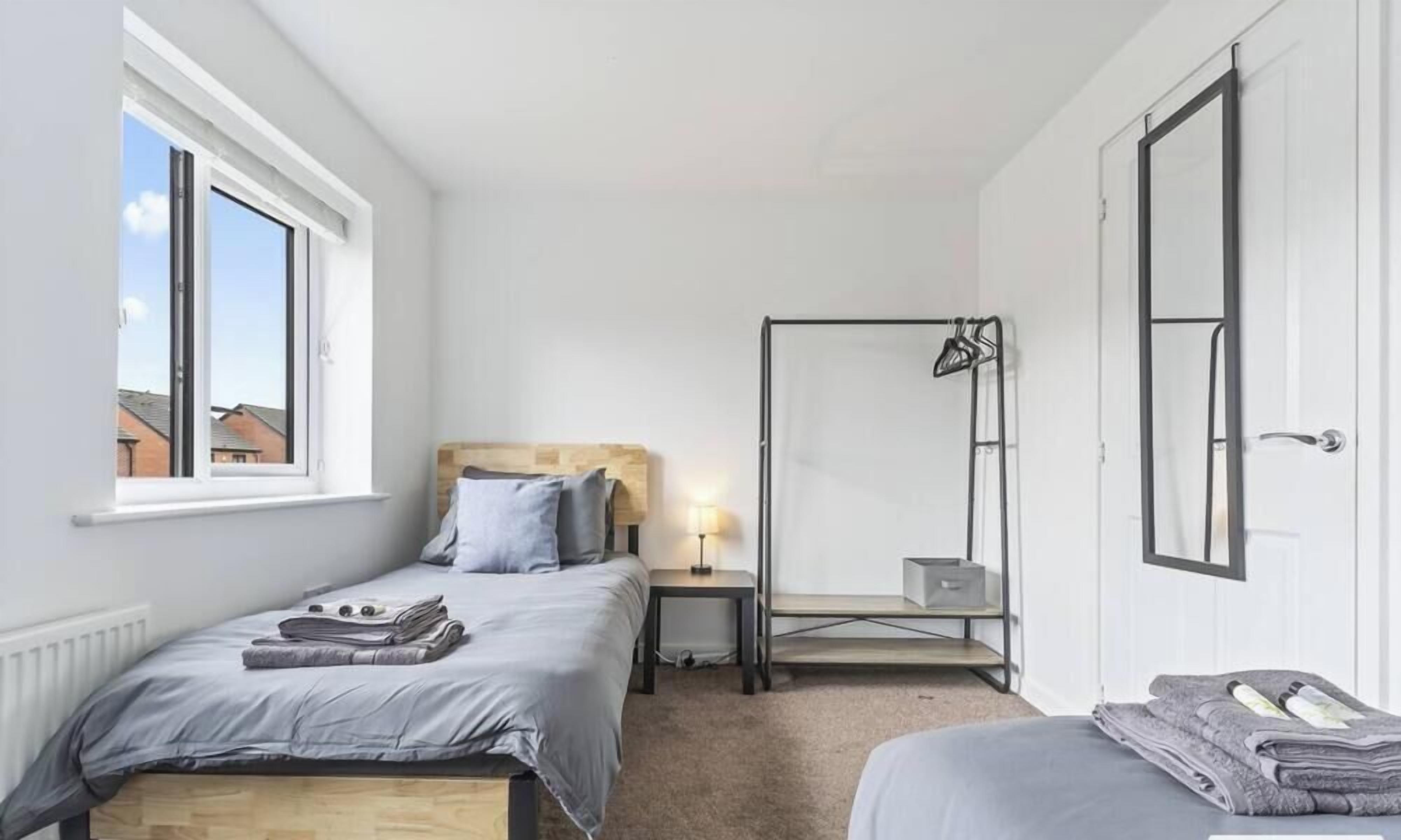 A bedroom with a bed, bedside table, lamp, and a window.