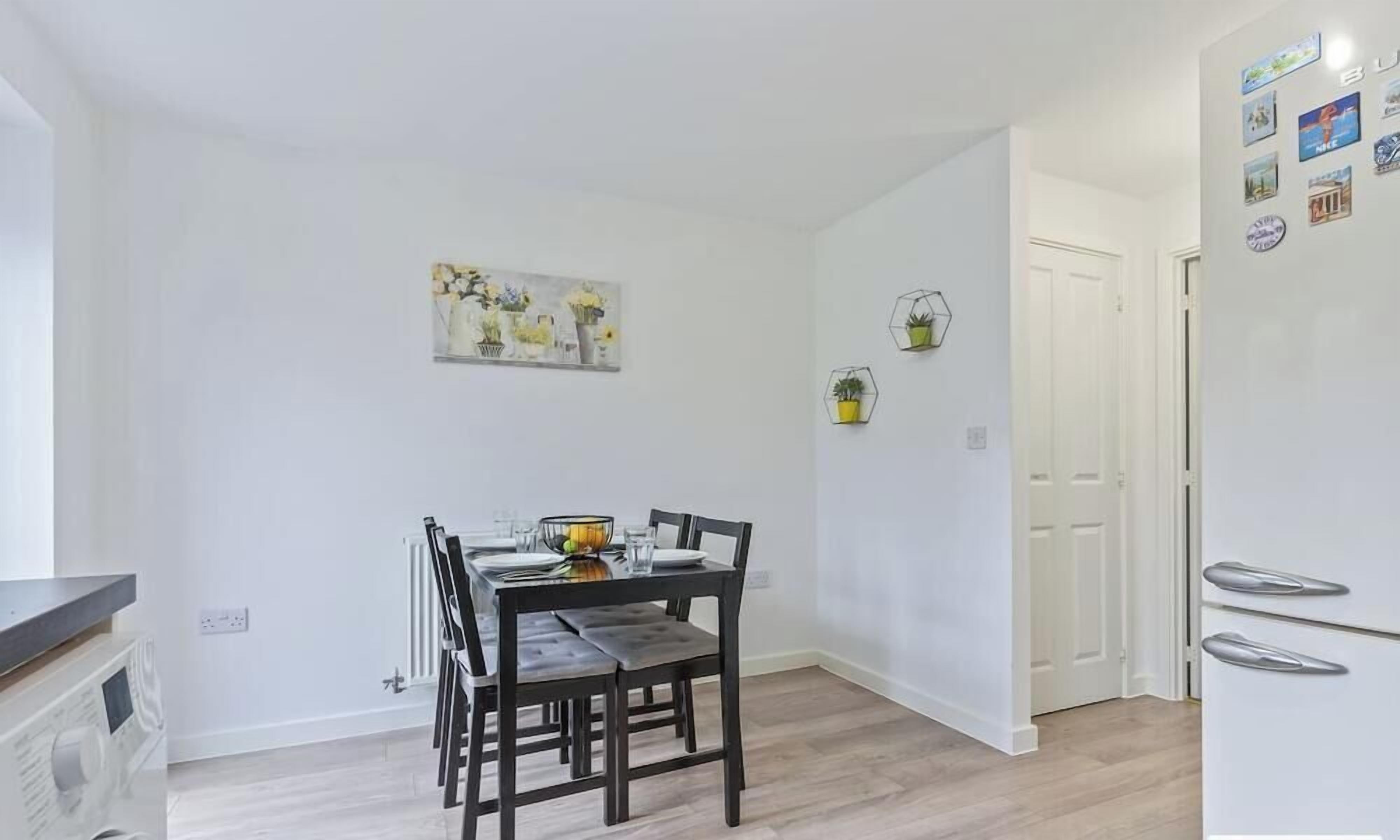 A dining area with a table set for two, a radiator, and a white door in the background.