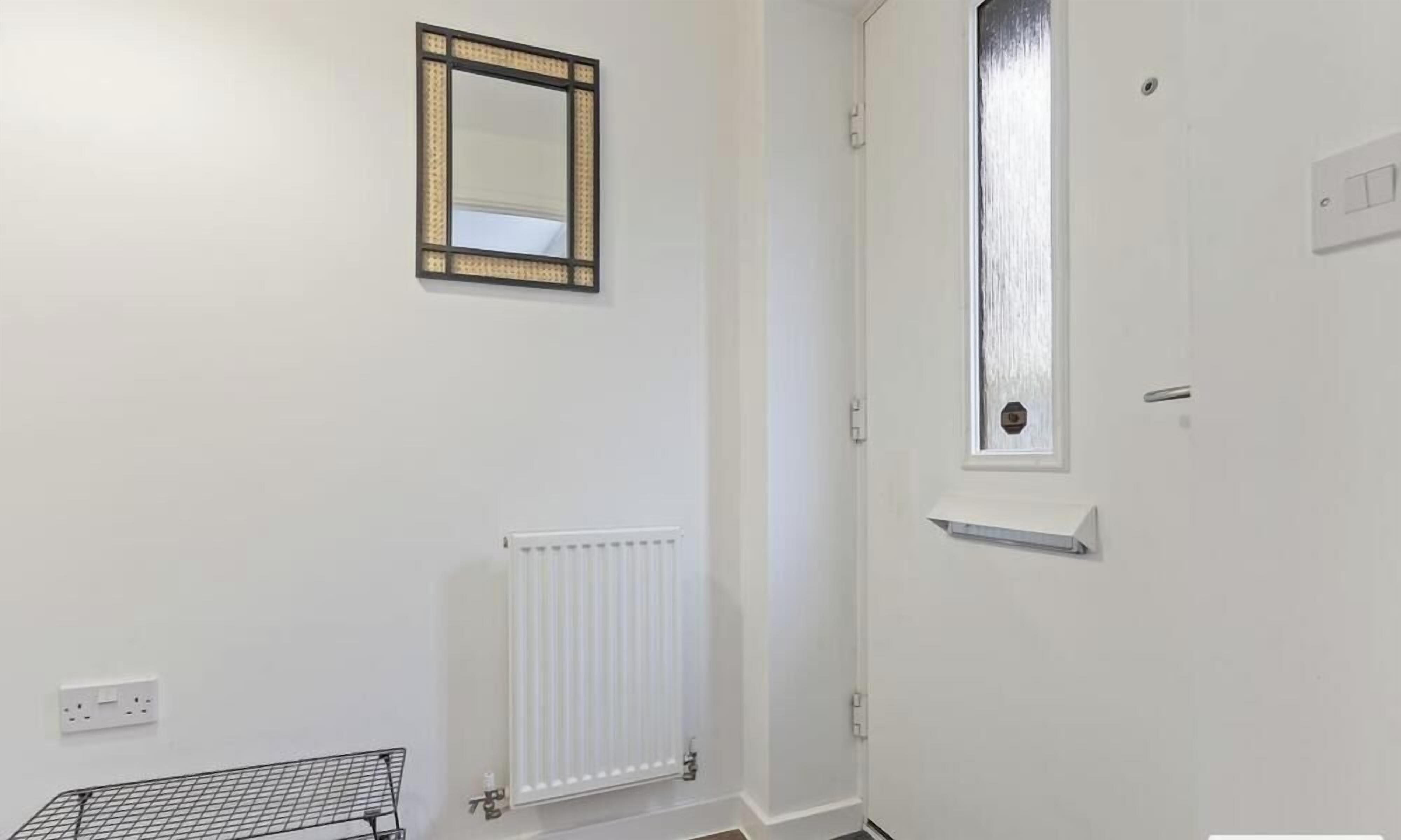A room with a white door, a small window, a radiator, and a metal shelf.