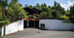 A modern building with a covered entrance, surrounded by dense greenery and a white wall. - Spacious Group Accommodation in Saalfelden (Saalfelden am Steinernen Meer)