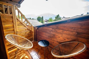 A wooden balcony with wicker chairs and a small table, overlooking a mountain. - Spacious Group Accommodation in Saalfelden (Saalfelden am Steinernen Meer)