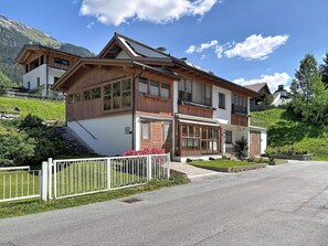 A two-story chalet with a sloped roof, wooden exterior, and a white facade.