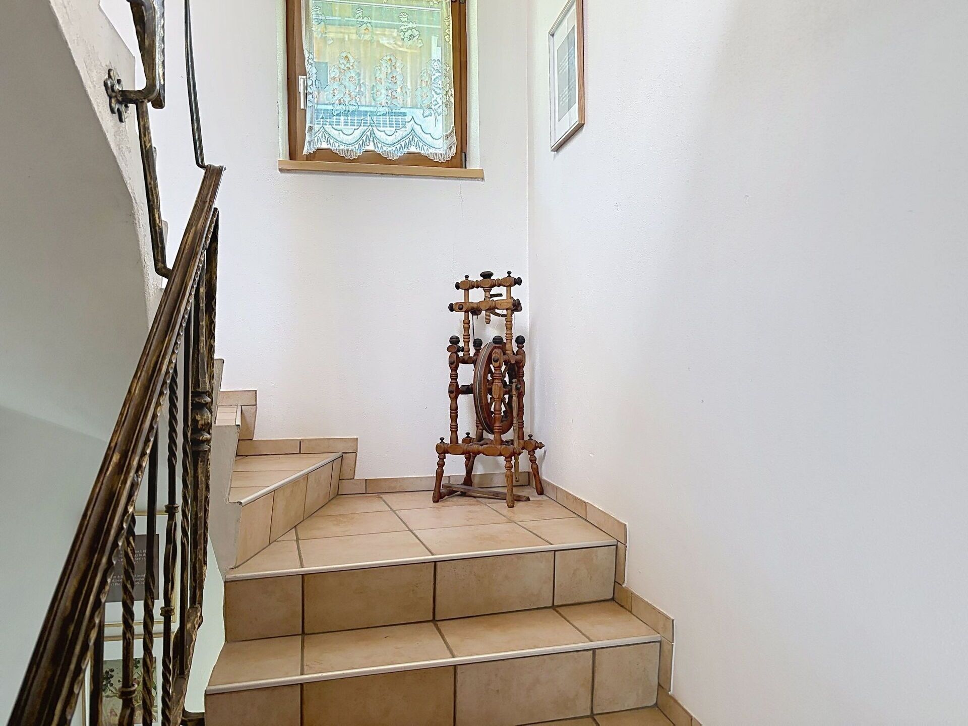 A staircase with a wooden spinning wheel at the bottom.