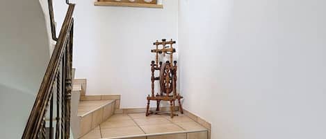 A staircase with a wooden spinning wheel at the bottom.