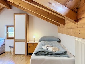 A bedroom with a bed, a nightstand, a lamp, and a window.