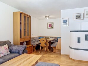 A compact living space with a wooden cabinet, a sofa, a dining table with chairs, and a refrigerator.