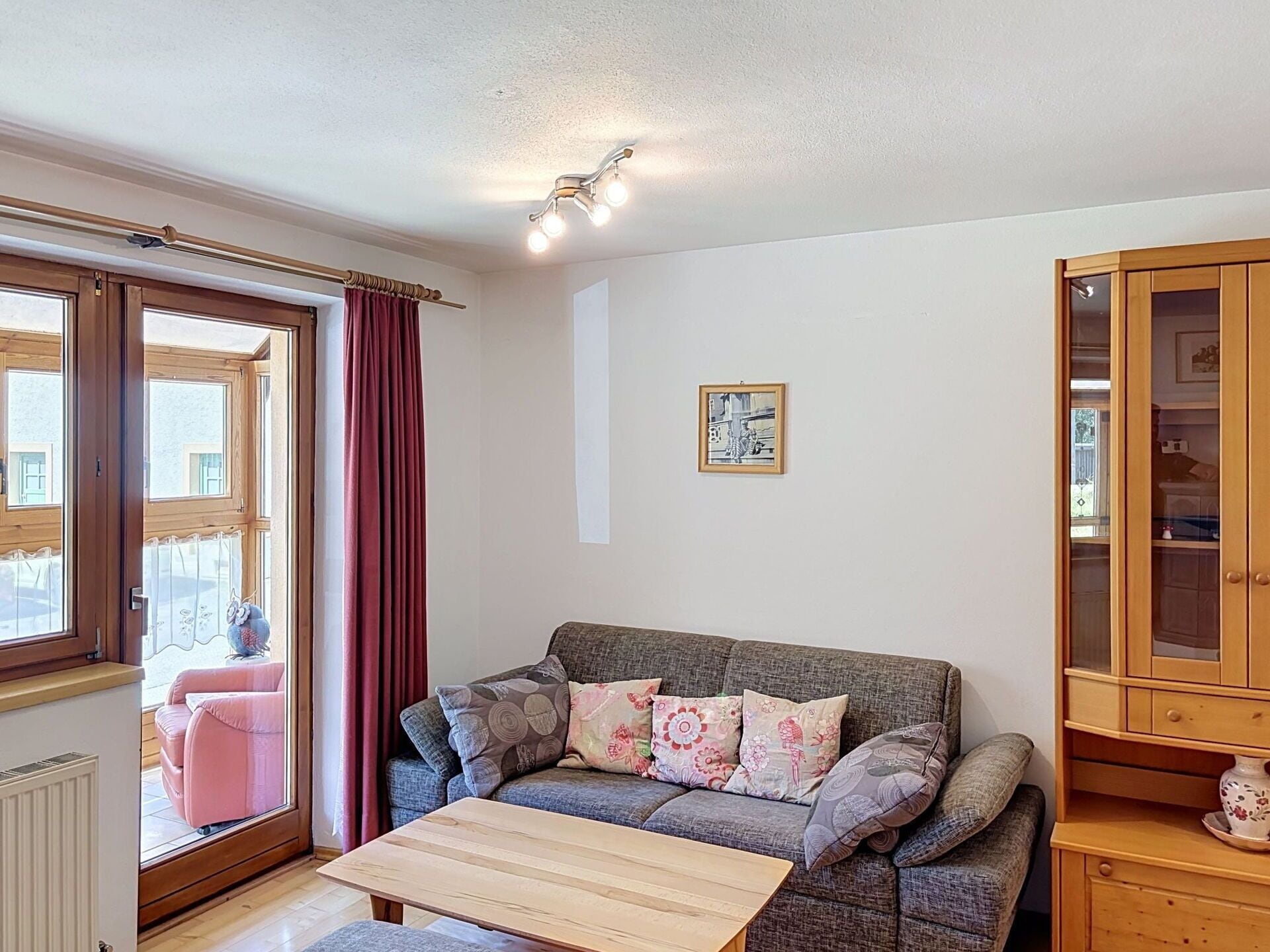 Een woonkamer met een bank, een salontafel, een kast en een raam met gordijnen.