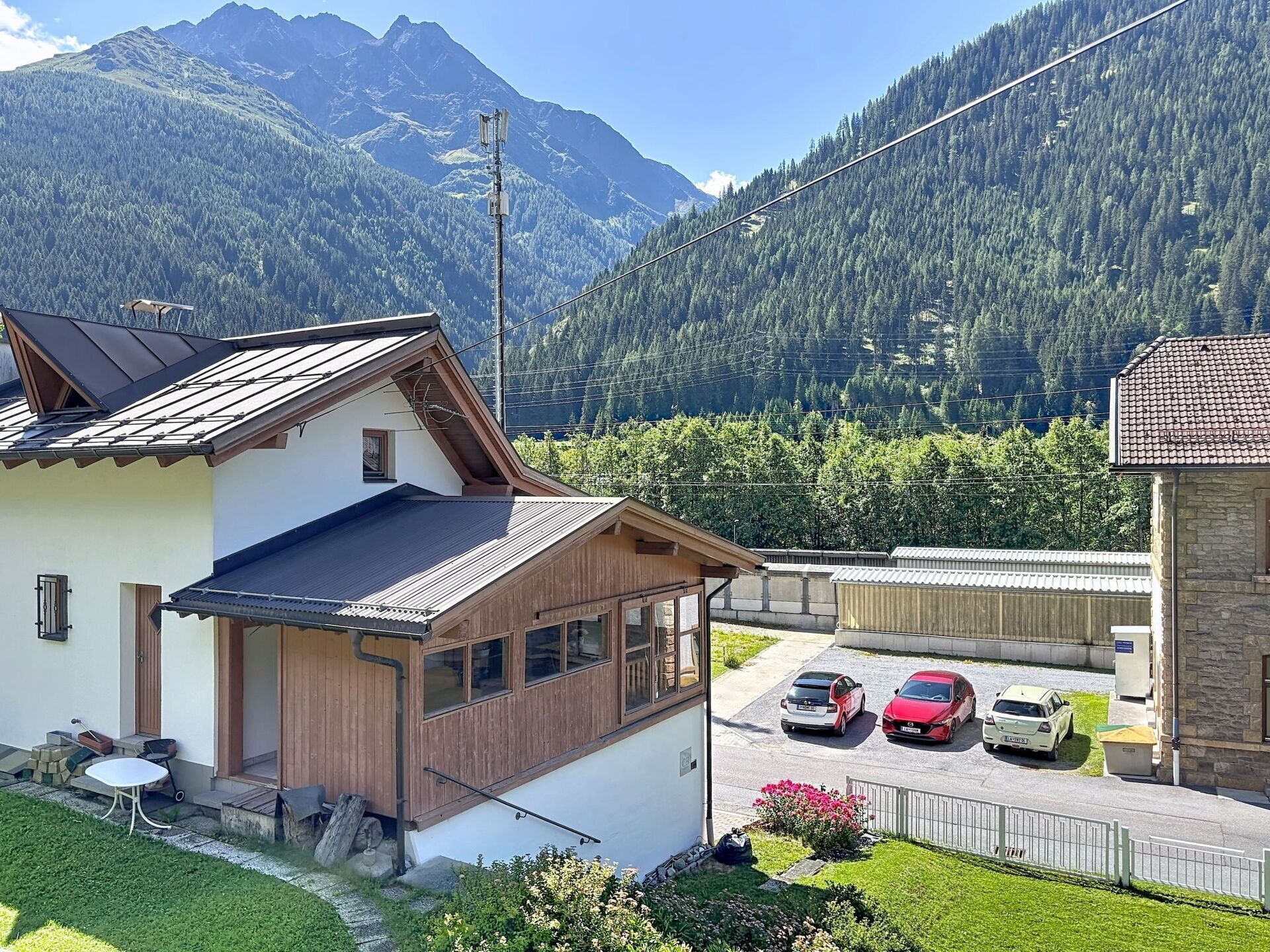 Eine Bergingerhütte mit schrägem Dach, einer kleinen Veranda und einem Parkplatz für drei Autos.