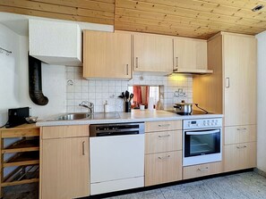 Eine Küche mit Holzschränken, einem Geschirrspüler, einem Backofen und einem Spülbecken.