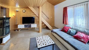 Ein Holzinnenraum mit einer Couch, einem Fernseher und einer Treppe.
