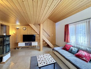 Ein Holzinnenraum mit einer Couch, einem Fernseher und einer Treppe.