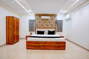 Ein Schlafzimmer mit einem großen Bett, einem Holzschrank und einer Klimaanlage an der Wand.