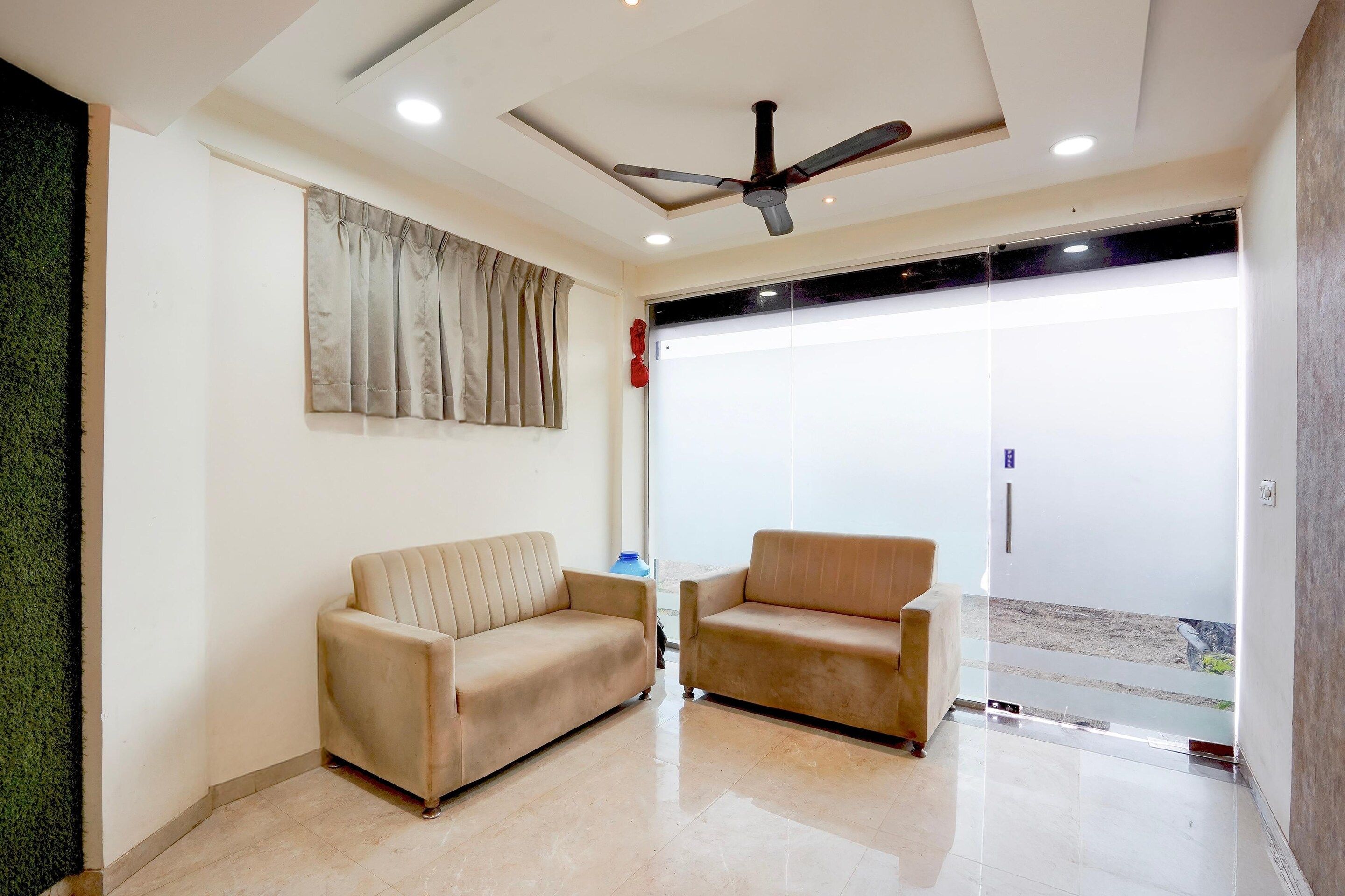 A modern living room with two sofas, a ceiling fan, and a large window.