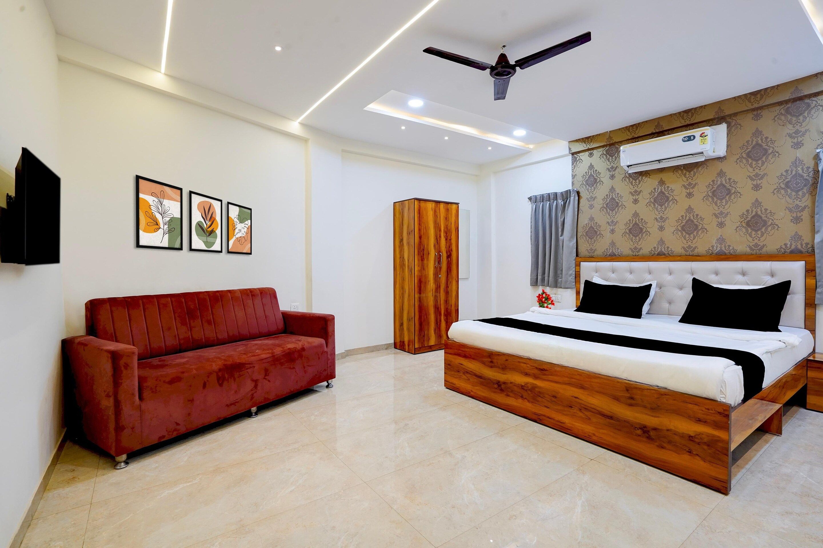 A modern bedroom with a wooden bed, a red sofa, and a ceiling fan.