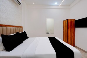 Ein Hotelzimmer mit einem Bett, einem Kleiderschrank, einem Spiegel und einer Klimaanlage.