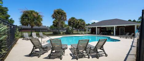 A swimming pool with lounge chairs and a covered seating area.