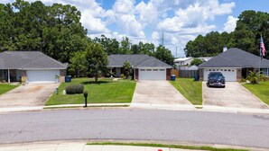 A residential street with houses, each with a garage and a driveway. - Coastal Orange Beach Retreat Minutes to the Beach, The Wharf & Family Fun (Orange Beach)