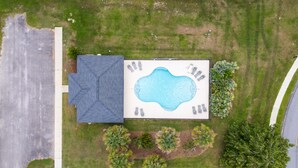 An aerial view of a property with a swimming pool, a covered patio, and a lawn. - Coastal Orange Beach Retreat Minutes to the Beach, The Wharf & Family Fun (Orange Beach)