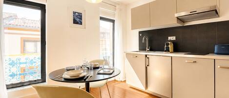 Una cocina moderna con comedor, que incluye una mesa redonda, sillas y vistas de la ciudad a través de amplios ventanales.