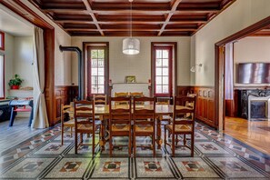 A dining room with a wooden table and chairs, a patterned floor, and a fireplace. - La Maison des Prés - Maison bourgeoise de 1890 (Montceau-les-Mines)