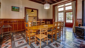 A dining area with a wooden table and chairs, a patterned floor, and a large window with curtains. - La Maison des Prés - Maison bourgeoise de 1890 (Montceau-les-Mines)