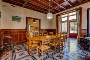 A dining area with a wooden table and chairs, a patterned floor, and a large window with curtains. - La Maison des Prés - Maison bourgeoise de 1890 (Montceau-les-Mines)