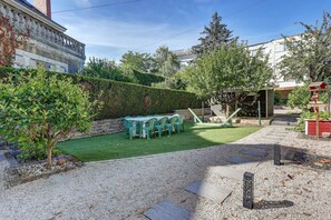 A courtyard with a green lawn, a seating area with chairs, and a gravel path. - La Maison des Prés - Maison bourgeoise de 1890 (Montceau-les-Mines)