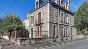 A two-story building with a symmetrical facade, multiple windows with shutters, and a central entrance. - La Maison des Prés - Maison bourgeoise de 1890 (Montceau-les-Mines)