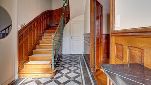 A wooden staircase with a geometric patterned floor, a white door, and a marble counter. - La Maison des Prés - Maison bourgeoise de 1890 (Montceau-les-Mines)