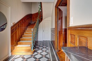 A wooden staircase with a geometric patterned floor, a white door, and a marble counter. - La Maison des Prés - Maison bourgeoise de 1890 (Montceau-les-Mines)