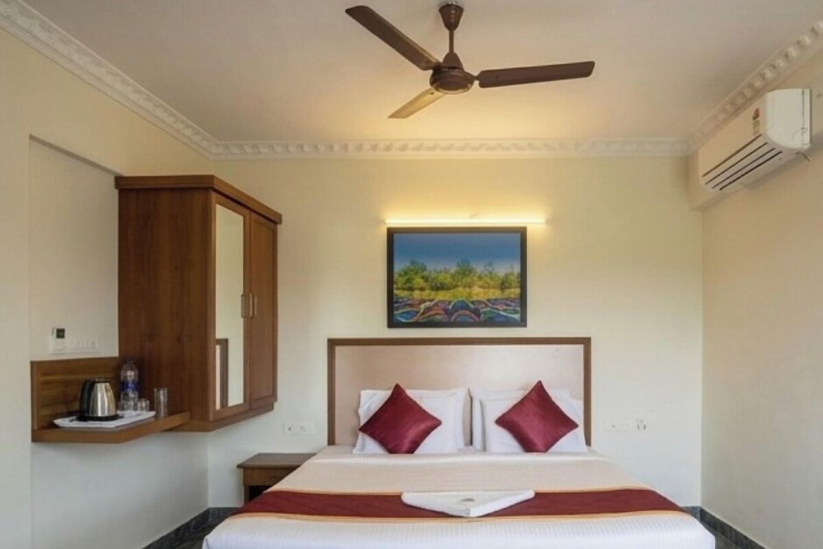 Una habitación de hotel con una cama, un ventilador de techo, un cuadro y un armario de madera.