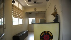 A hallway with a bench, a door, and a wall-mounted sign for Pop Tavern. - Hotel Poptavern Townbridge (Thiruvananthapuram)