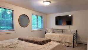 Een slaapkamer met een bed, een stapelbed, een spiegel en een televisie.