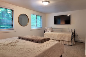 A bedroom with a bed, a bunk bed, a mirror, and a TV.