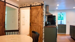 Een keuken met een houten deur, een eettafel met stoelen en uitzicht op de omgeving.