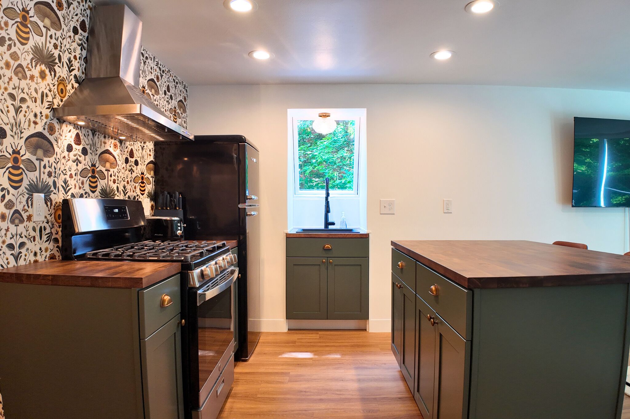 A modern kitchen with a central island, a built-in oven, and a stainless steel range hood.