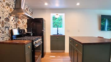A modern kitchen with a central island, a built-in oven, and a stainless steel range hood.