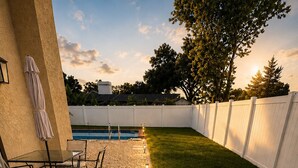 Ein Garten mit Pool, Terrassenmöbeln und einem weißen Zaun.