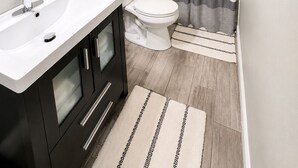 Ein modernes Badezimmer mit einem weißen Waschbecken, schwarzen Schränken, einer Toilette und einer Duschvorhang.