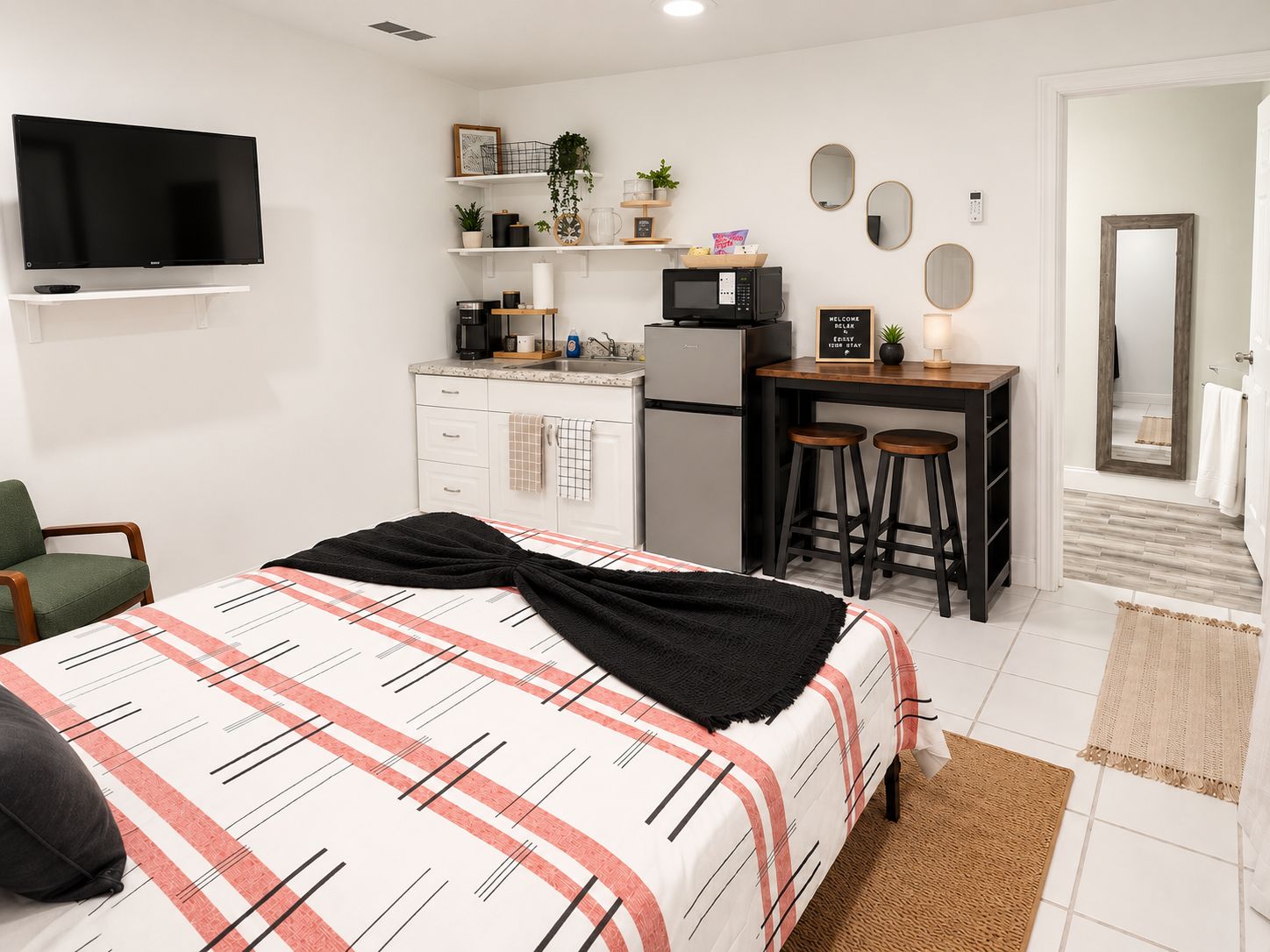 Habitación de hotel moderna con cama, escritorio, televisor y kitchenette.