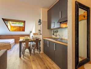 A compact kitchen with a dining area, a loft bedroom with a skylight, and a large mirror. - Nice apartment for 3 people with WIFI, TV, terrace and pets allowed (Cepina)
