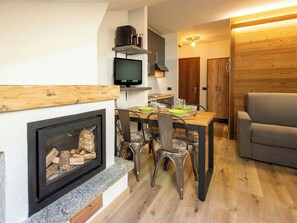 A modern kitchen with a built-in TV, a dining area with a table set for two, and a cozy seating area with a sofa. - Nice apartment for 3 people with WIFI, TV, terrace and pets allowed (Cepina)