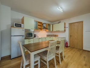 A compact kitchen with a microwave, oven, and a wooden dining table with chairs.